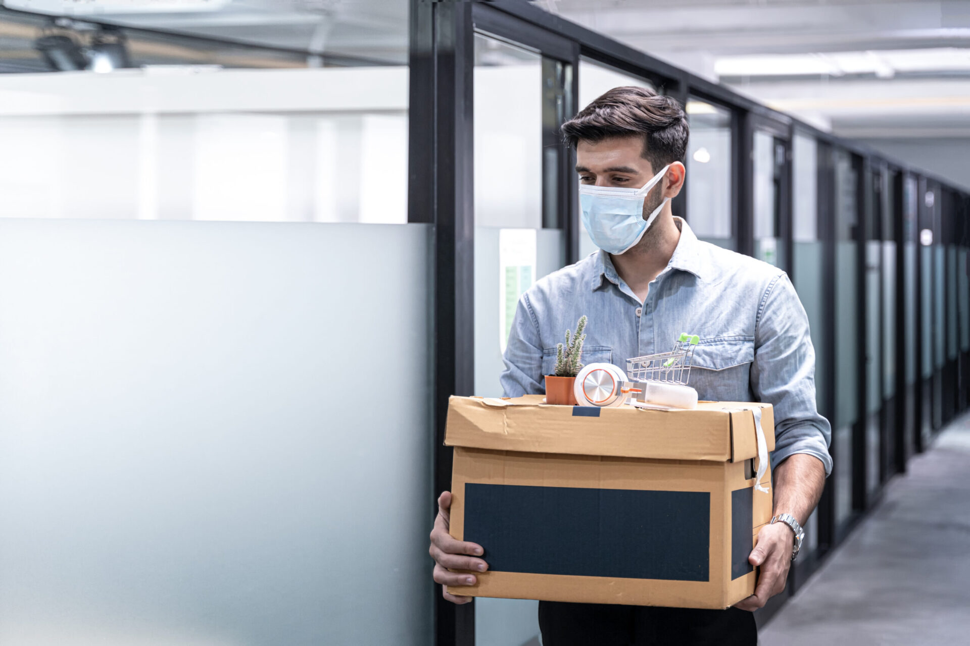 Man with mask packs things in office